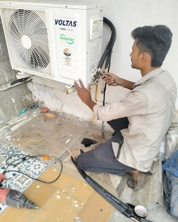 Hamid Corporation technician servicing a Voltas AC unit